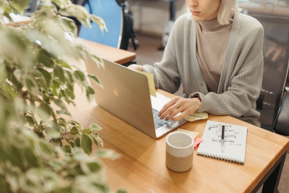 Woman typing on her laptop with an action plan beside her to grow an email list effectively