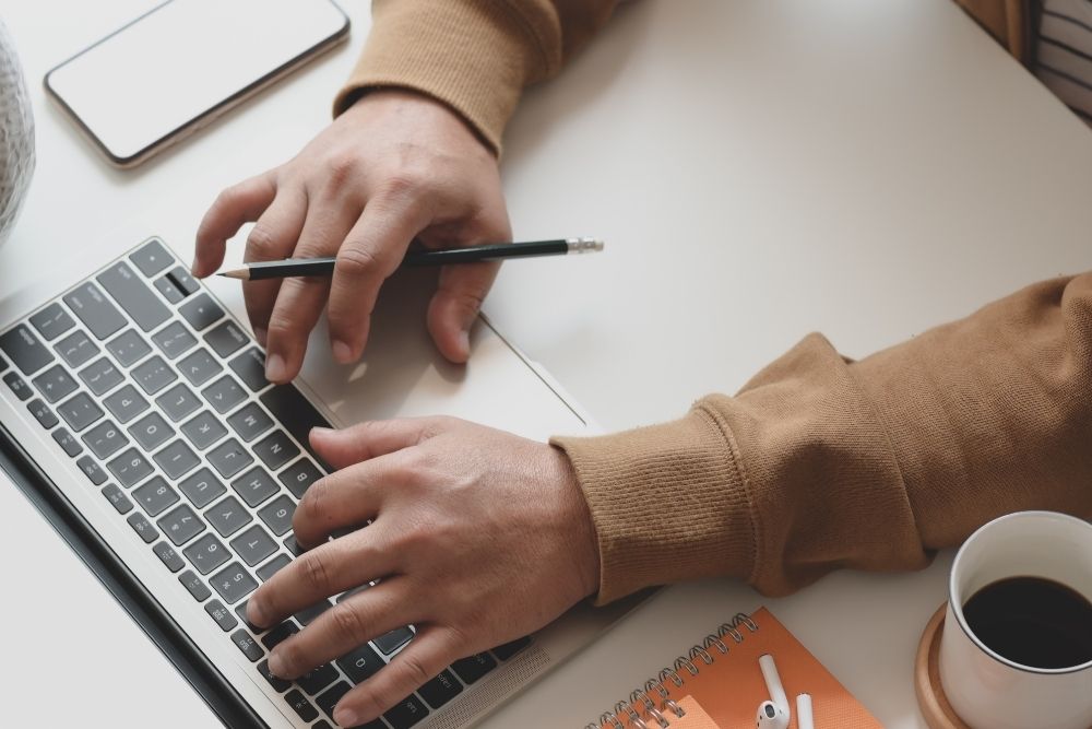 Close-up of a hand typing on a laptop to create content that helps grow an email list