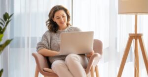 Smiling woman typing on her laptop while working on strategies to grow an email list
