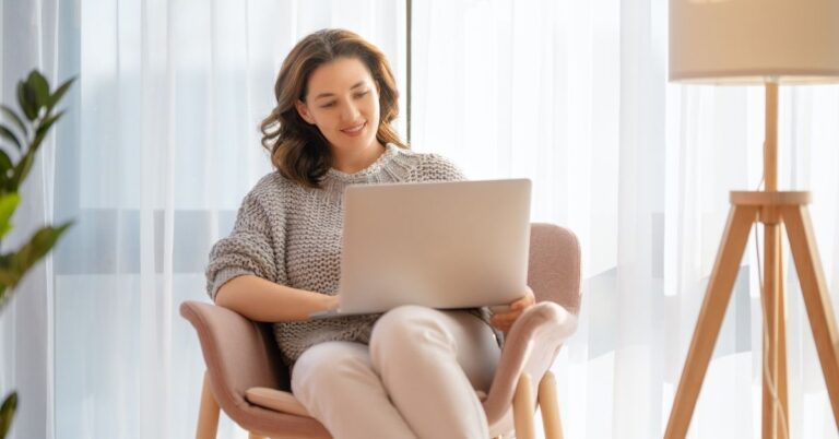 Smiling woman typing on her laptop while working on strategies to grow an email list