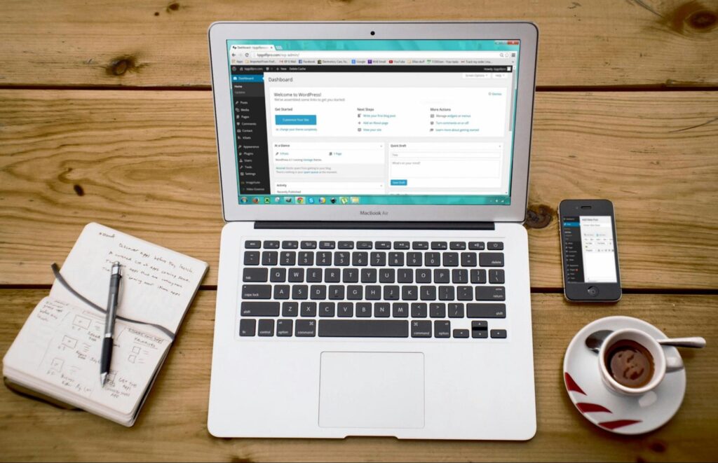 Flatlay of laptop showing WordPress admin dashboard with coffee and notebook, symbolizing content management ease.