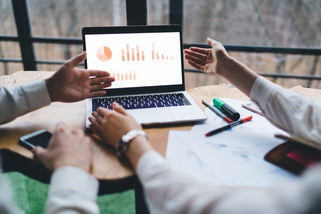 Two people discussing SEO analytics and website performance graphs on a laptop screen.