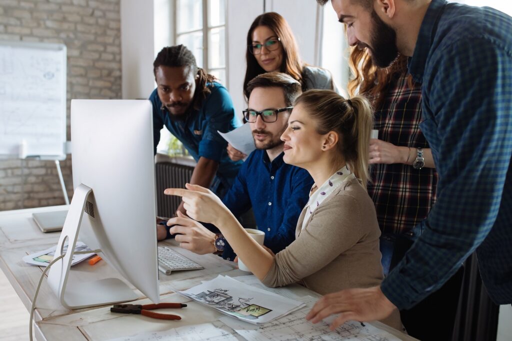 Group of web designers discussing ideas in front of a computer, representing the WordPress community.