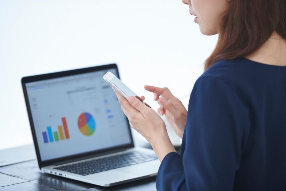 Small business owner checking ad analytics on phone and laptop after the Andromeda update.