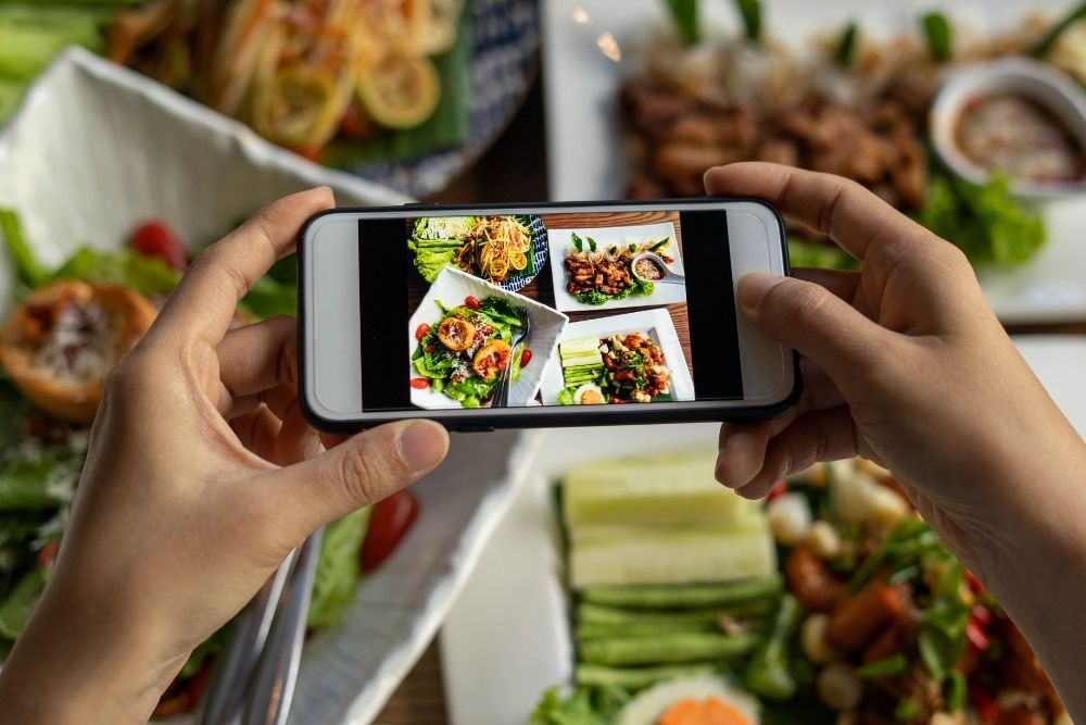Restaurant owner taking high-quality food photos for Google Business Profile optimization and posts.
