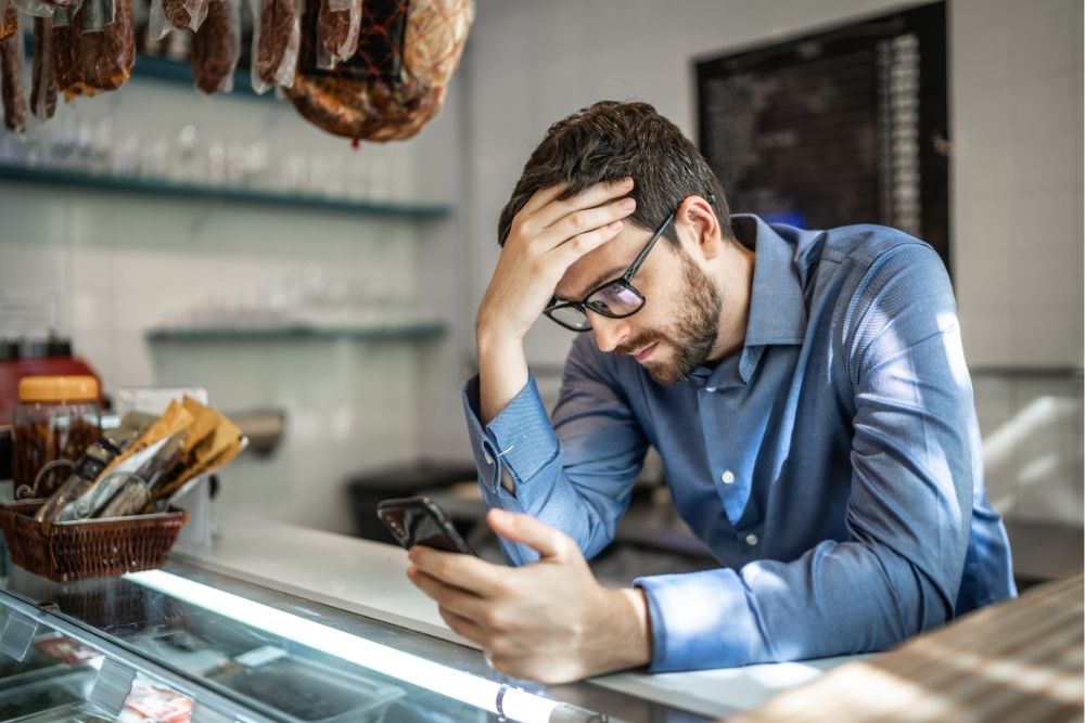Business owner looking stressed while reading feedback online before writing a professional reply to Google Reviews.