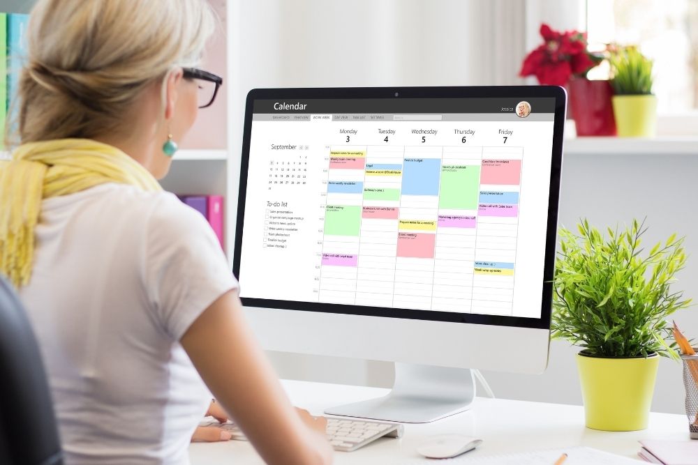 Operations manager reviewing monthly metrics, software dashboards, and schedules on a computer.