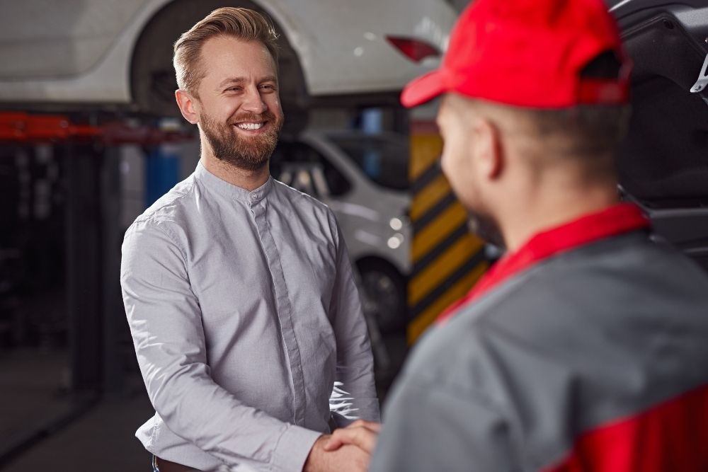 elieved homeowner shaking hands with a local service technician at the end of a successful repair job.