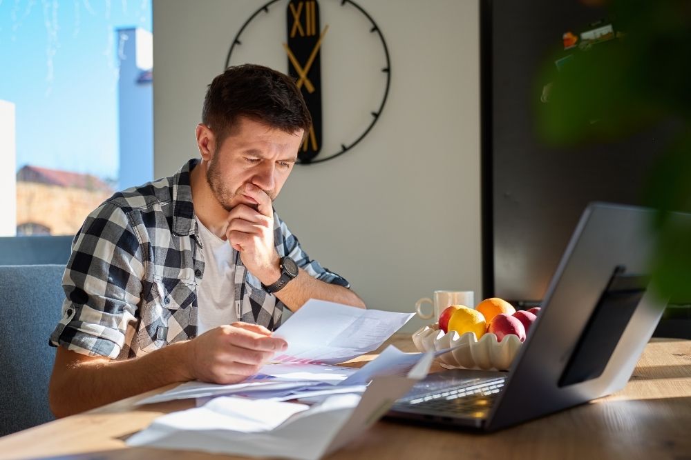 Local contractor analyzing documents and online business profiles at a desk.